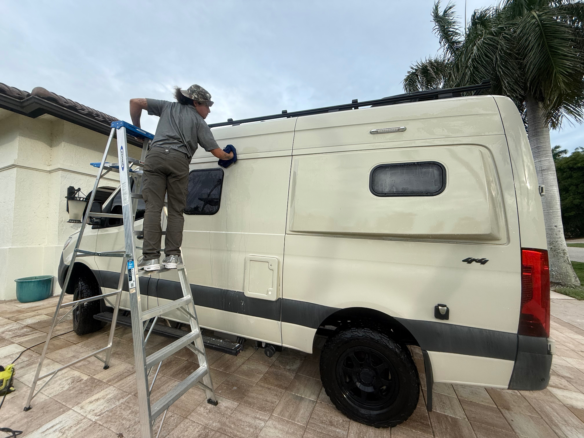J&C Elite Auto Spa owner detailing a large RV on a ladder